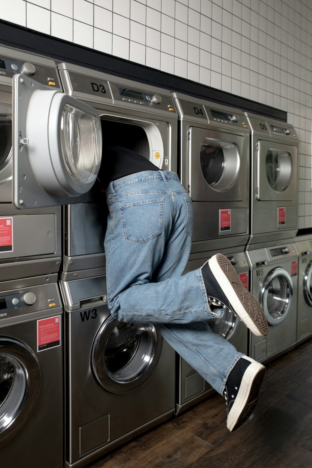 Person leaning halfway into an open laundromat washing machine looking for something. Used to relate to idea of searching for SEO NZ.